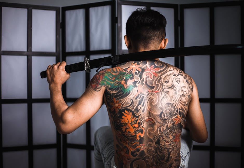 Back view of a tattooed man with a katana