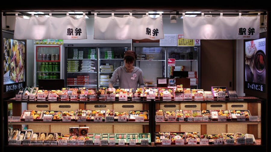 Woman arranging bento boxes in a Tokyo shop, showcasing Japanese bento packaging